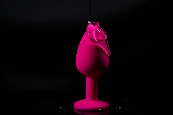 Sex toy. Black butt plag and donut on a pink background. Useful