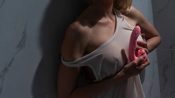 一个身穿白色背心的女人站在淋浴间里 手里拿着一个弯曲的粉色性爱玩具 — 图库照片