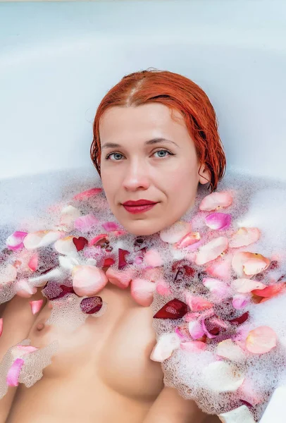 性感女人躺在有玫瑰花瓣的浴室里 — 图库照片